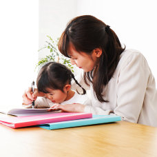 woman assisting a kid to write